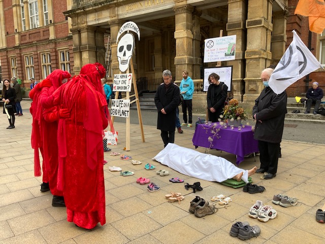 Red Rebels and mourners attend the corpse of COP26.  Die in at Leamington Town Hall